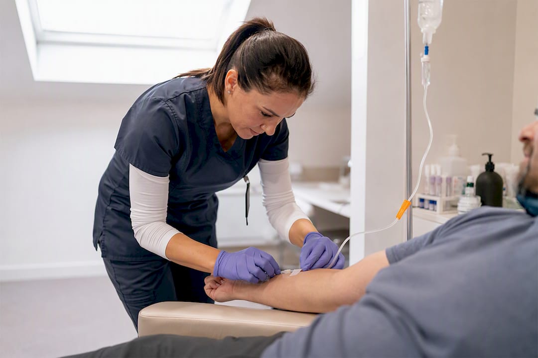Nurse adjusting IV on patient in detox room